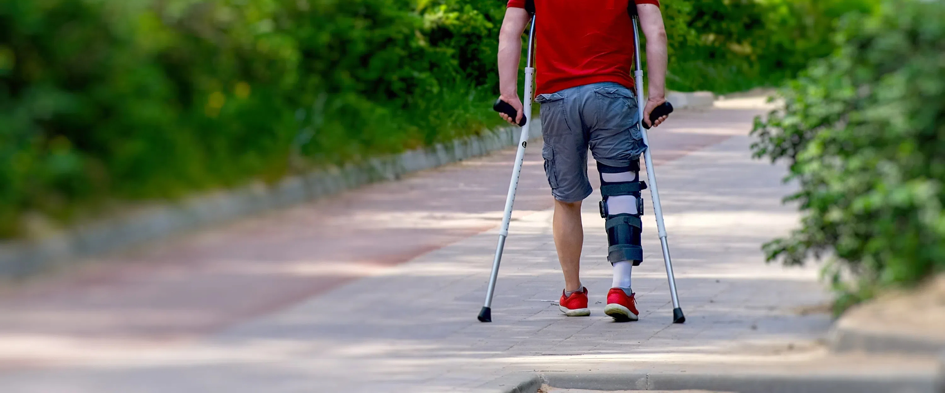 determined man knee brace using crutches